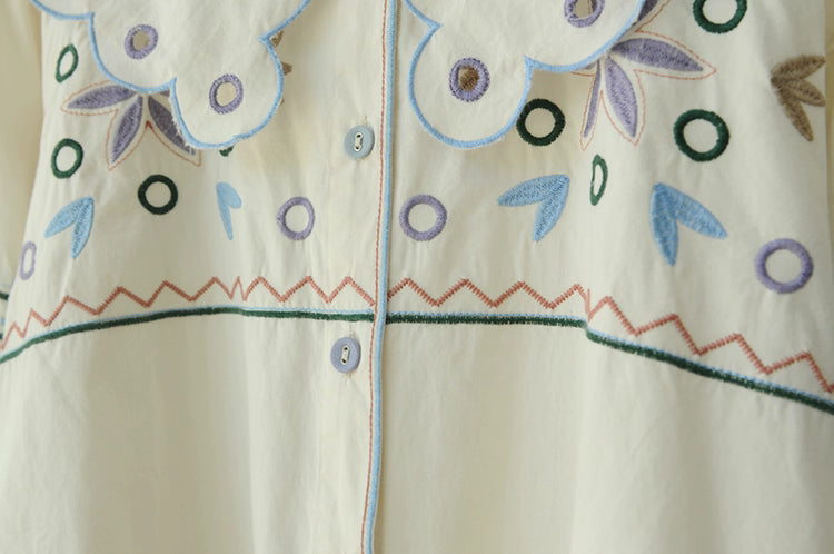 Close-up of a garment with floral embroidery on a beige background