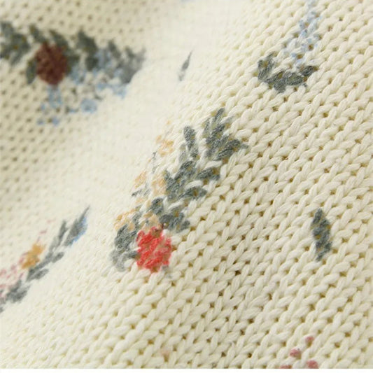 Close-up of a knitted garment with floral patterns on a wooden surface.