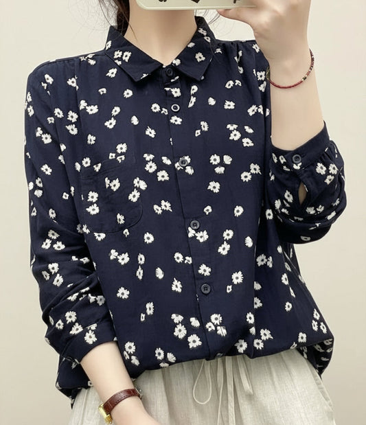 Person wearing a navy blue floral patterned shirt taking a mirror selfie.