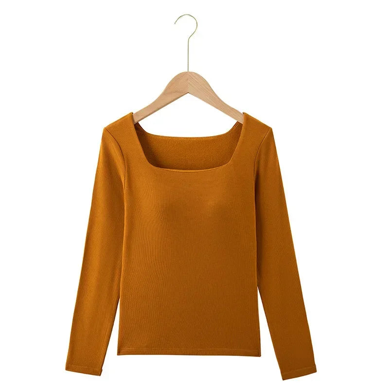 Mustard yellow long-sleeve top on a wooden hanger against a white background