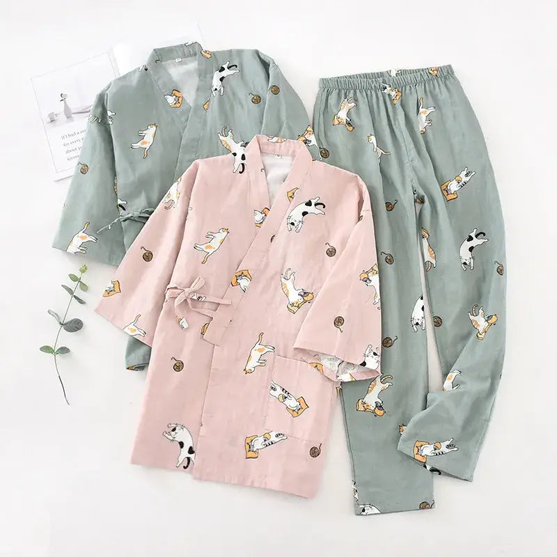 A set of cartoon cat-themed pyjamas in pink and green colors with printed cats and other small designs.