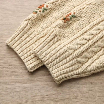 Knitted sweater with floral embroidery on a wooden surface