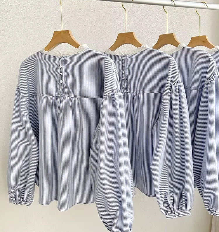 Blue and white striped blouse on hangers against a neutral background