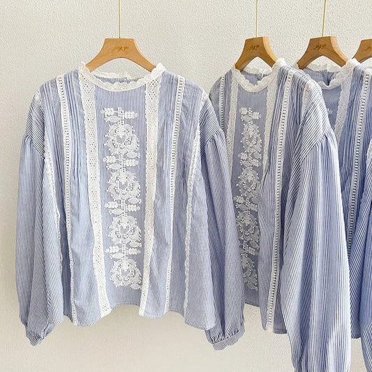 Blue and white striped shirts with lace details on hangers against a neutral background