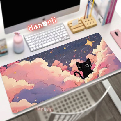 A colorful desk mat featuring an illustration of a black cat with star-like patterns in the background, placed on a desk with a computer monitor, keyboard, and other desk items around.