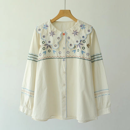 Embroidered blouse on a wooden hanger against a plain background