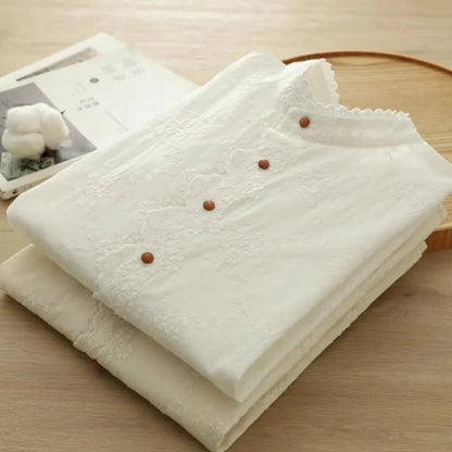 folded white shirts with brown buttons on a wooden surface