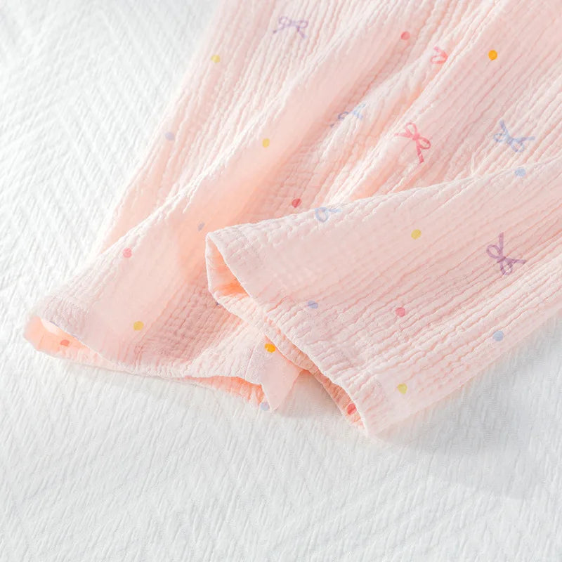 Pink textured fabric with colorful dots on the pajama trousers on a white background
