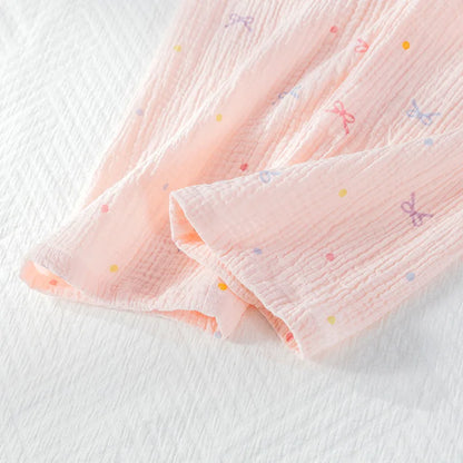 Pink textured fabric with colorful dots on the pajama trousers on a white background