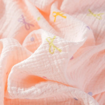 Close-up of a soft, textured fabric with colorful patterns on a light pink pyjama.