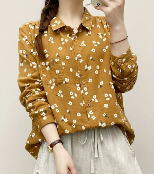 Person wearing a mustard yellow floral shirt on a white background