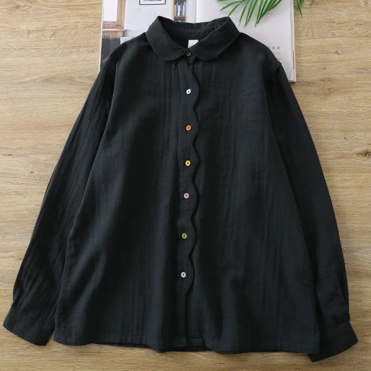 Black shirt with colorful buttons on a hanger against a home interior background