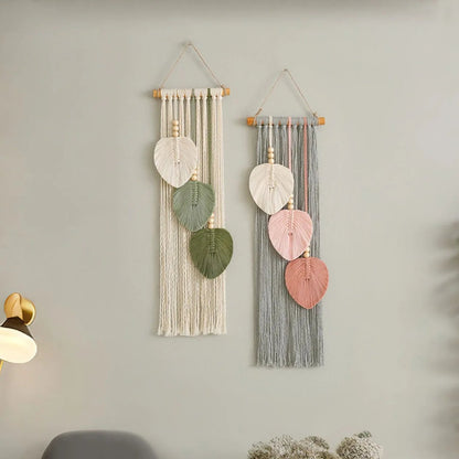 Two wall hangings with leaf-shaped decorations on a light gray wall.